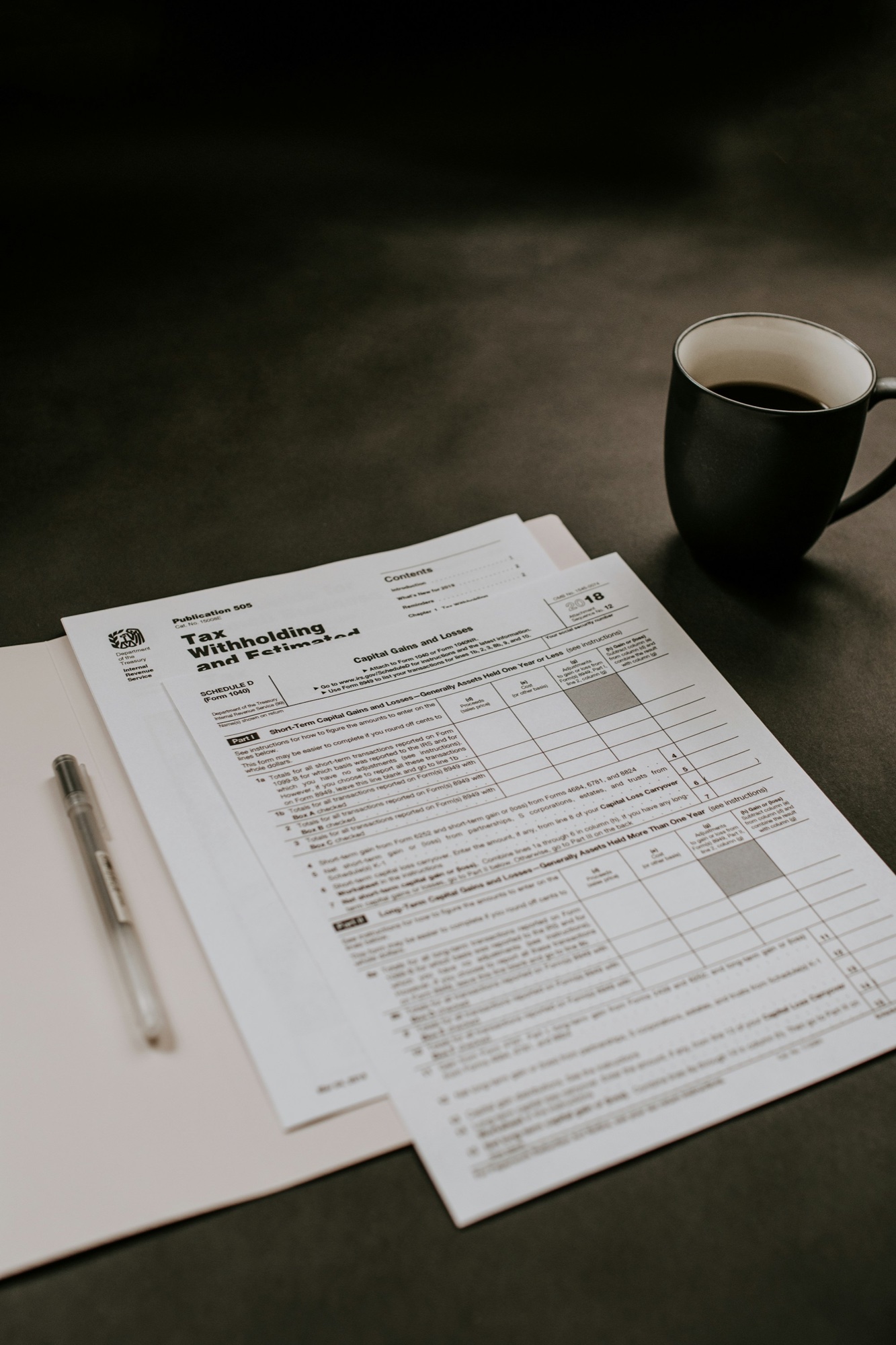 IRS tax withholding and estimated-payments worksheet on a desk with coffee and pen